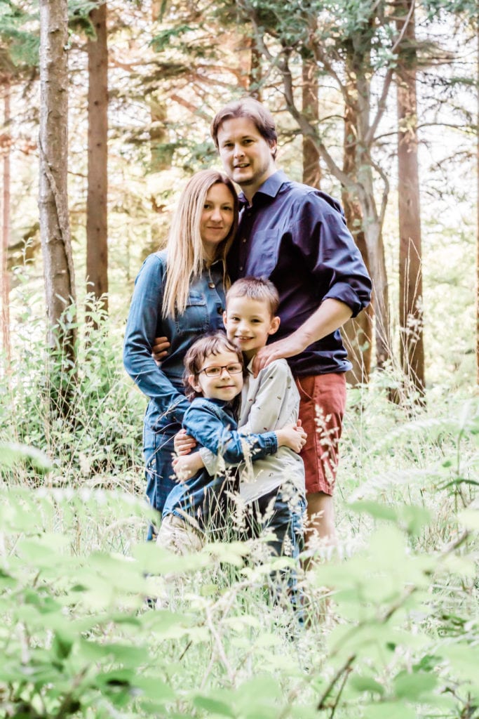 family standing in the woods